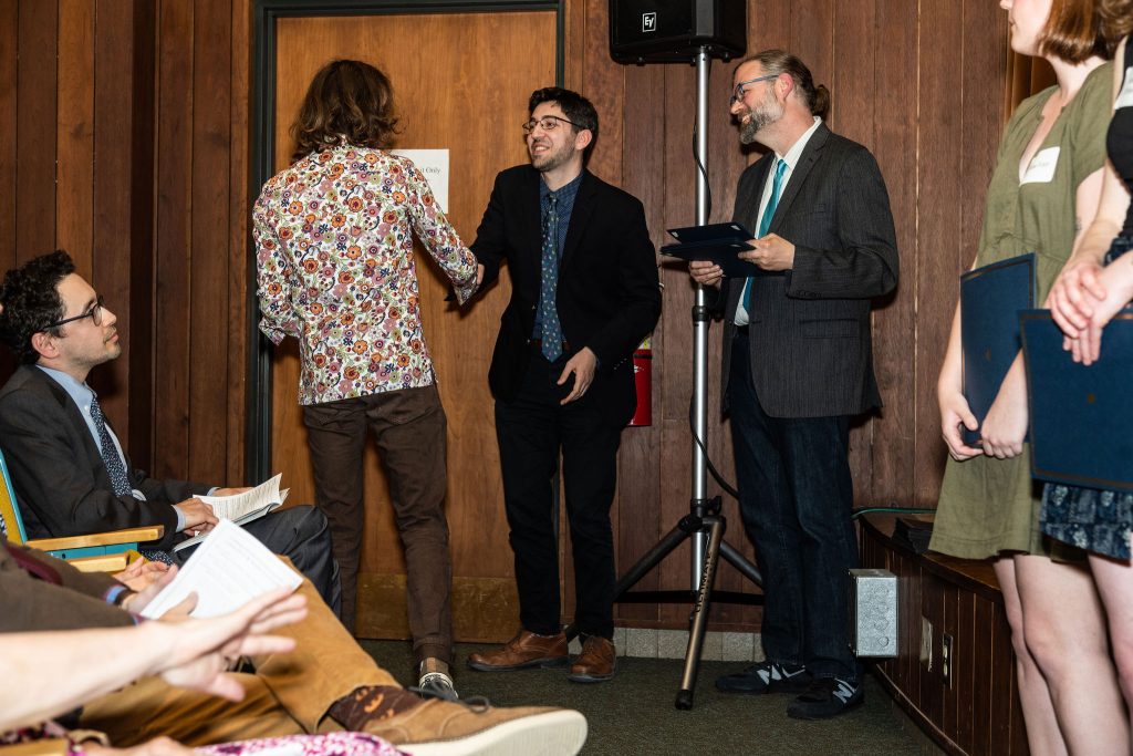 Student receives their award certificate from Professor Brandon Bloch and Undergraduate Advisor, Scott Burkhardt.