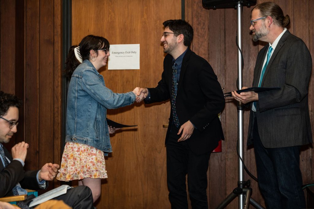Student receives their award certificate from Professor Brandon Bloch and Undergraduate Advisor, Scott Burkhardt.