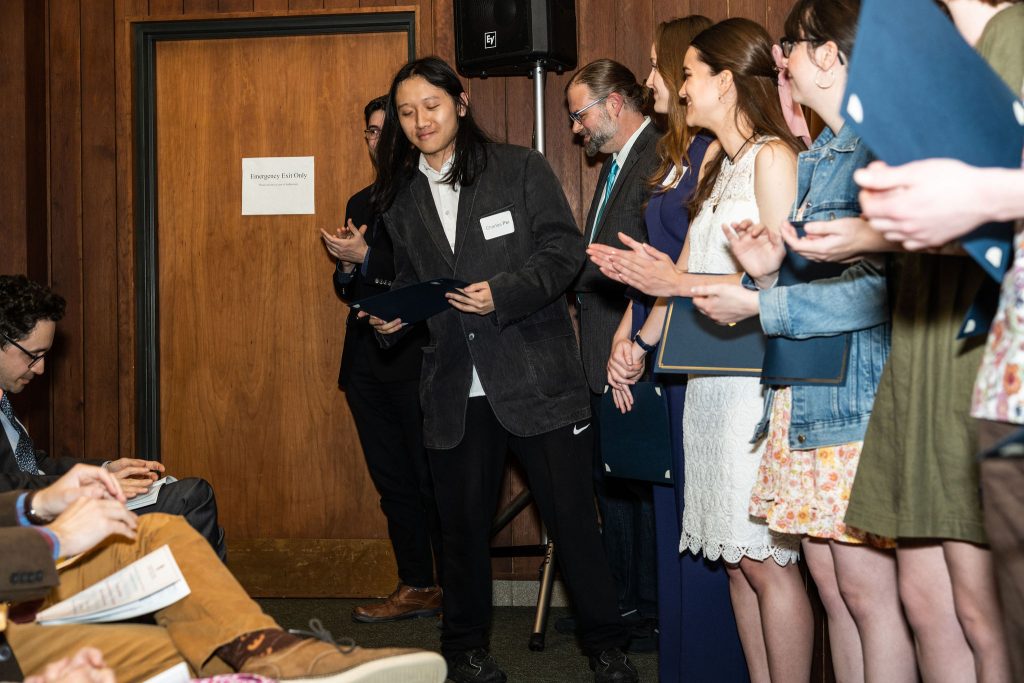 Student receives their award certificate from Professor Brandon Bloch and Undergraduate Advisor, Scott Burkhardt.