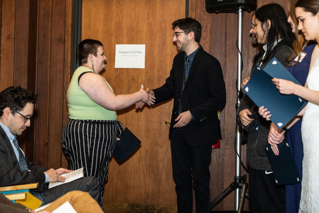 Student receives their award certificate from Professor Brandon Bloch and Undergraduate Advisor, Scott Burkhardt.