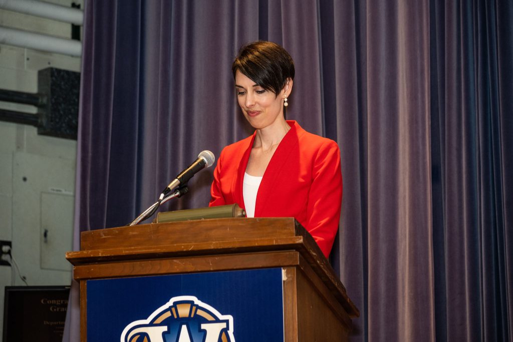 Professor Gloria Whiting recognizes graduates by name as they walk in front of the stage.